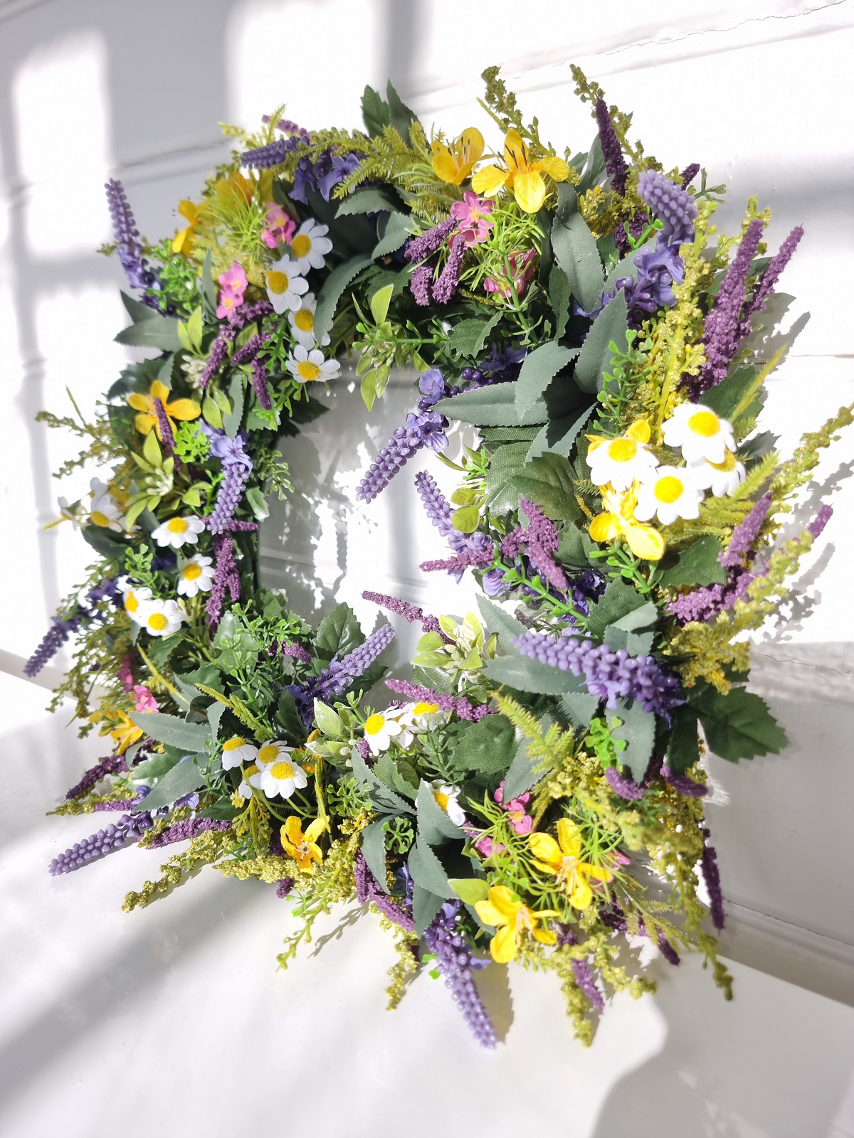 Konstgjord krans med blommor. Besök blickfång.se