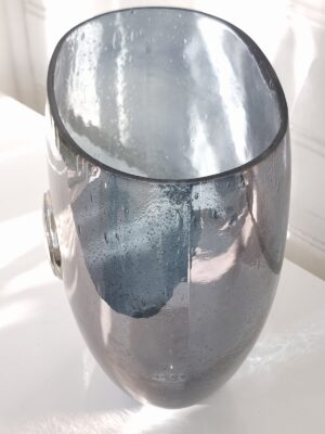 Grå glasvas med silver emblem. Besök blickfång.se