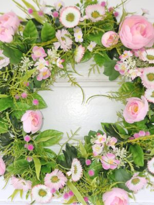 Konstgjord krans med bellis och ranuncel. Besök blickfång.se