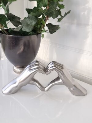 Händer i silver formade som hjärta. Besök blickfång.se