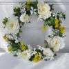 Konstgjord krans med blommor i vitt och gult. Besök Blickfång.se