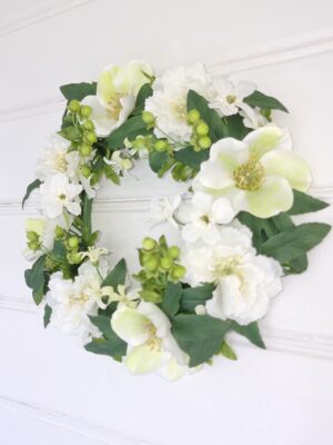 Konstgjord dörrkrans med vita blommor. Besök Blickfang.se