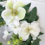 Konstgjord dörrkrans med vita blommor. Besök Blickfang.se