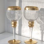 Ett par ljuslyktor i glas på fot med guld. Besök Blickfång.se