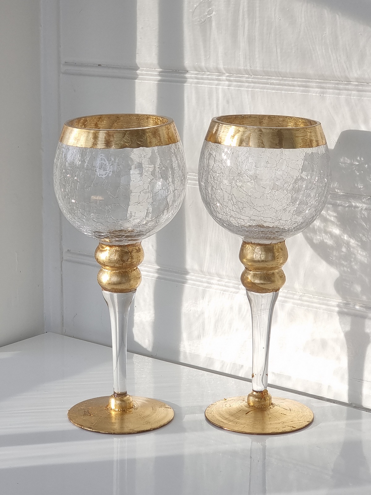 Ett par ljuslyktor i glas på fot med guld. Besök Blickfång.se