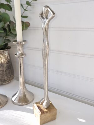 Smal dam staty i silver på träfot. Besök blickfång.se