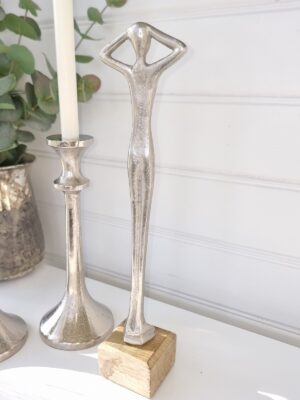 Smal dam staty i silver på träfot. Besök blickfång.se