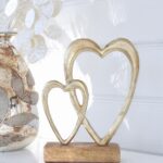 Hjärtan ihopp i guld på träfot för dekoration. Besök Blickfång.se