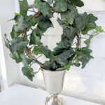 rund kruka på fot i ruff silver metall med en murgröna